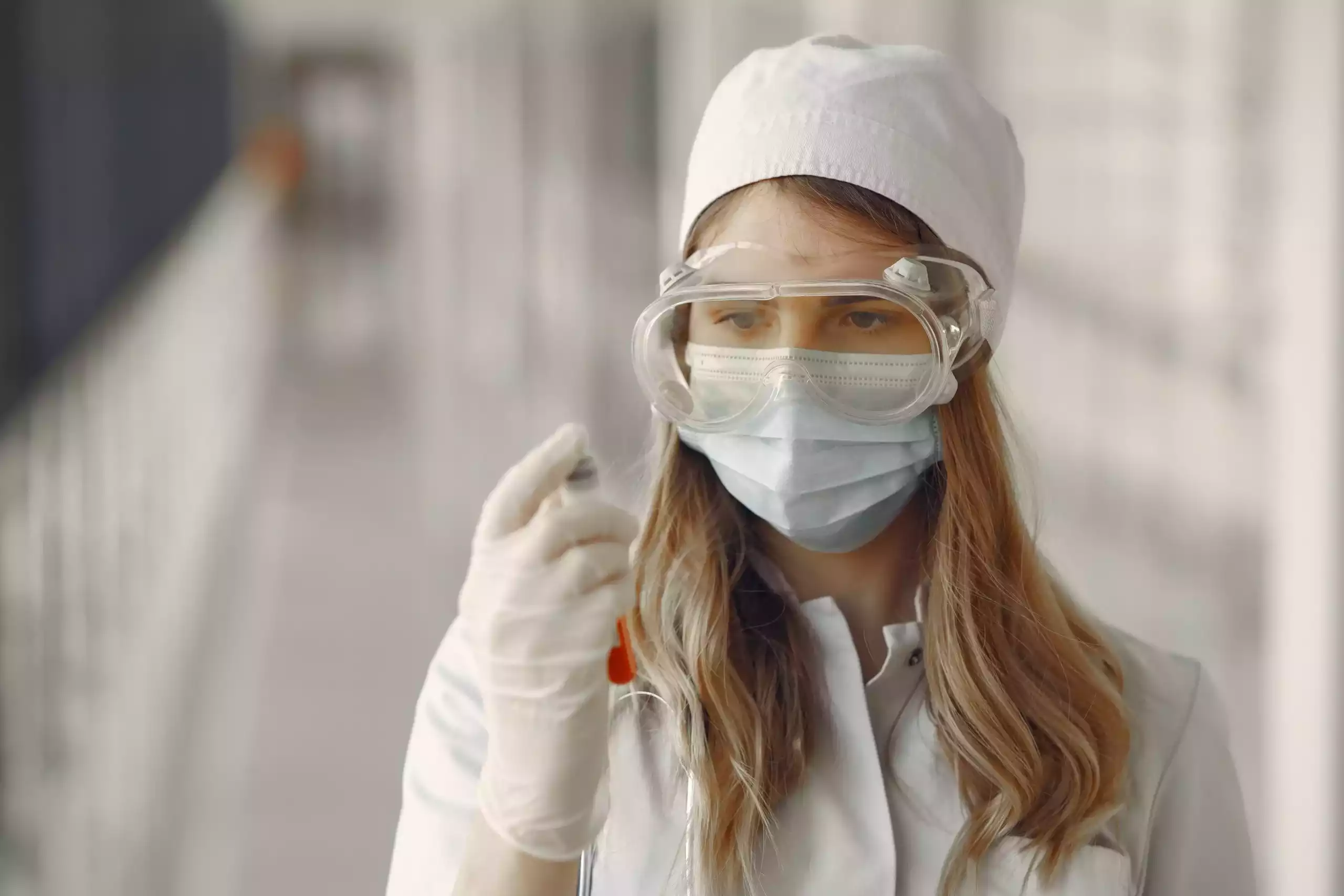 A woman scientist wearing safety goggles while performing consumer product safety testing