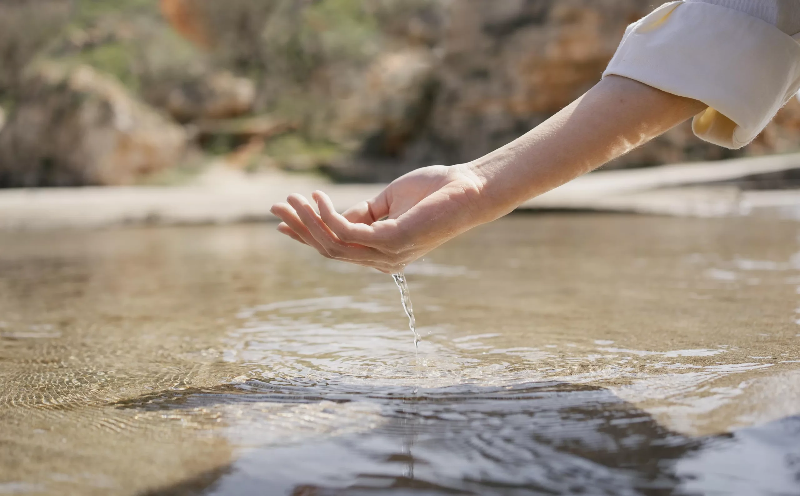 A hand checking water in an open surrounding